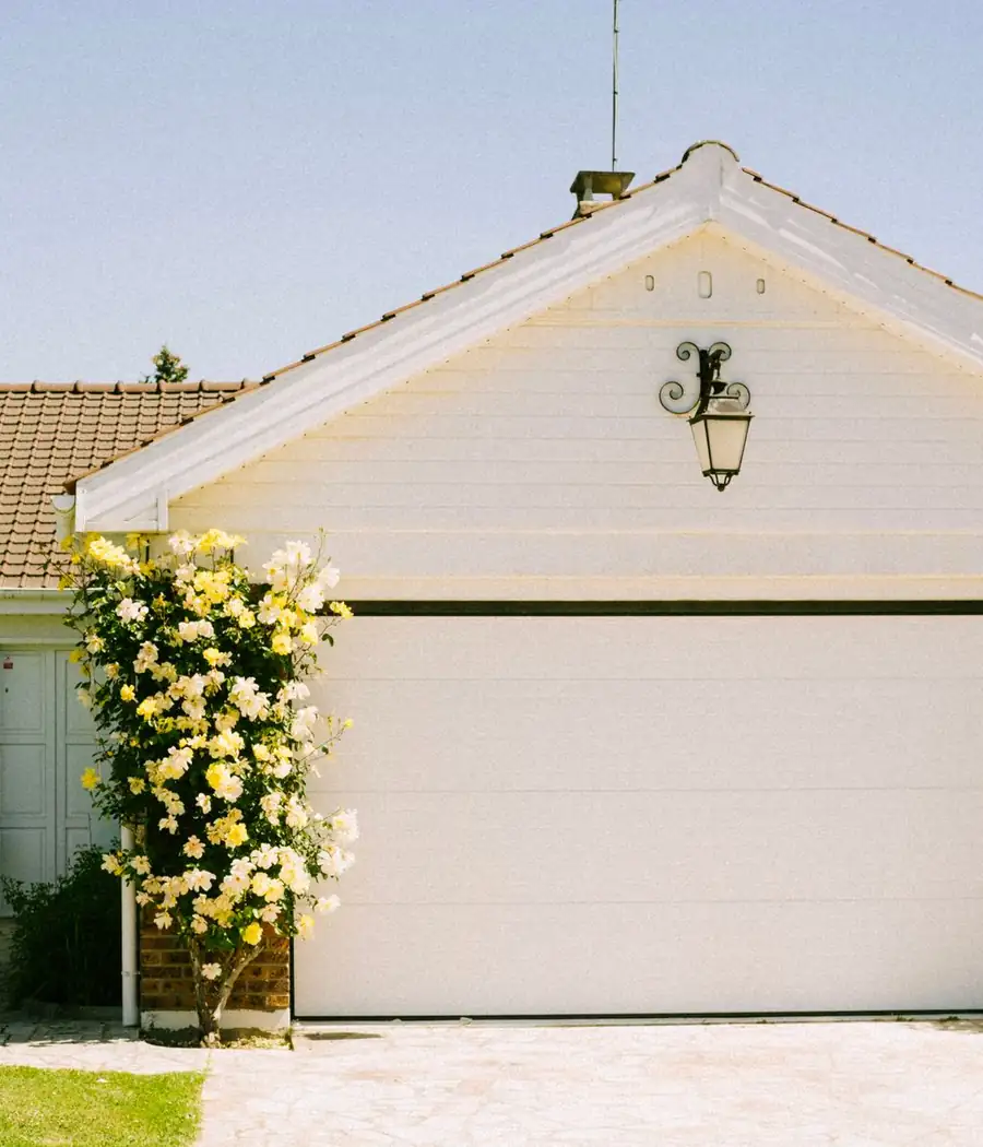White sectional garage door framed by climbing roses